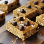 To make No-Bake Cookie Dough Protein Bars, you need these main ingredients: - 1 cup almond flour - 1 cup rolled oats - 1/2 cup vanilla protein powder - 1/4 cup pure maple syrup - 1/4 cup creamy almond butter - 1 teaspoon pure vanilla extract - 1/2 cup dark chocolate chips (preferably mini) - 1/4 teaspoon fine sea salt These ingredients give the bars their great taste and texture. Almond flour and rolled oats form the base. The vanilla protein powder adds protein and flavor. Maple syrup and almond butter bind everything together while adding sweetness. You can customize your bars with some fun add-ins: - Chopped nuts (like walnuts or pecans) - Dried fruit (like cranberries or raisins) - Coconut flakes - Different flavors of protein powder Adding these can change the flavor and texture. It lets you make the bars your own. You can mix and match based on your taste. These bars are not just tasty; they are also nutritious. Each bar has: - Calories: around 150 - Protein: about 6 grams - Carbohydrates: 15 grams - Fats: 7 grams These numbers can vary based on your chosen add-ins. They provide good energy and are a great snack after workouts. Enjoy these bars without feeling guilty! First, grab a large mixing bowl. Add 1 cup of almond flour. Then, add 1 cup of rolled oats. Next, mix in 1/2 cup of vanilla protein powder. Stir all the dry ingredients well. Make sure there are no clumps. A good mix helps the bars stay together later. Now, take another bowl for the wet mix. Combine 1/4 cup of pure maple syrup and 1/4 cup of creamy almond butter. Add 1 teaspoon of pure vanilla extract. Whisk everything until it’s smooth. You want no lumps in this mix. A smooth blend makes the bars tasty. Next, pour the wet mix into the dry mix. Stir it continuously. Use your hands to knead the dough gently. This helps blend everything well. Once combined, fold in 1/2 cup of dark chocolate chips. Add in 1/4 teaspoon of fine sea salt. Mix until the chocolate chips are spread out evenly. Prepare an 8x8 inch baking pan by lining it with parchment paper. Leave some paper hanging over the edges. This makes it easy to lift the bars out later. Transfer the dough into the pan. Press it down firmly to make an even layer. Place the pan in the refrigerator for at least 30 minutes. This time helps the bars firm up. After they are set, lift the parchment paper to remove the bars. Cut them into squares or rectangles. Enjoy your tasty treats! To get the right texture for your bars, use fresh ingredients. Almond flour should be fine and soft. Rolled oats add a nice chewiness. If you want a smoother feel, you can blend the oats into a powder. This will change the texture but still taste great. Also, knead the dough gently with your hands. This helps mix all the ingredients well. For easy prep, gather some handy tools. You will need a large mixing bowl and a smaller bowl for wet ingredients. A whisk makes mixing easier. A spatula helps to combine everything well. Use a sharp knife for cutting the bars neatly. Finally, parchment paper is key. It keeps your bars from sticking and makes for easy removal. Want to make your bars even tastier? Add some fun extras! Try using different nut butters, like peanut or cashew. You can also mix in dried fruits like cranberries or raisins for a sweet touch. If you like crunch, sprinkle in chopped nuts or seeds. For a twist, use flavored protein powder, like chocolate or cookies and cream. These small changes can make your bars unique and delicious! {{image_4}} You can easily switch up the flavors of these protein bars. For a peanut butter twist, replace almond butter with creamy peanut butter. You will get a rich, nutty taste. If you love chocolate chip cookie dough, add more chocolate chips for a sweeter treat. You can also mix in some cocoa powder for a chocolatey flavor. Want to make these bars vegan? Just use plant-based protein powder and maple syrup. For a gluten-free option, ensure your oats are certified gluten-free. This way, everyone can enjoy these tasty treats, no matter their diet. Adding mix-ins makes these bars even better. Try chopped nuts for extra crunch. Dried fruit like cranberries or raisins can add sweetness. You can also use seeds like chia or flax for a healthy boost. Get creative and use what you love! To keep your no-bake cookie dough protein bars fresh, store them in an airtight container. This helps to seal in moisture and flavor. You can use a glass or plastic container with a tight lid. If you prefer, wrap each bar in plastic wrap or foil for individual servings. This makes it easy to grab one on the go! If you want to keep your bars longer, freezing is a great option. First, cut the bars into squares or rectangles. Then, wrap each piece in plastic wrap or aluminum foil. Place the wrapped bars in a freezer-safe bag or container. They can last up to three months in the freezer. When you're ready to eat one, just take it out and let it thaw in the fridge. These protein bars stay fresh for up to a week in the fridge. Keep an eye on their texture and smell. If they feel dry or smell off, it’s time to toss them. For the best taste, eat them within the first few days. Remember, the more fresh, the better the flavor! Yes, you can change the protein powder. Use any flavor you like. For example, chocolate or peanut butter powder will add more taste. Just make sure it measures the same as the vanilla protein powder. This way, the texture stays right. You can tell when the bars are set if they are firm to the touch. After chilling for at least 30 minutes, they should feel solid. If they still seem soft, leave them in the fridge longer. A good test is to press down lightly; they should not bounce back. These protein bars are full of healthy ingredients. They have protein from the powder and almond butter. The oats give you fiber, which is good for your digestion. Almond flour is low in carbs and high in healthy fats. The dark chocolate adds antioxidants, making these bars a tasty and healthy snack. To avoid dry bars, mix your wet ingredients well. Ensure the almond butter and maple syrup blend smoothly. If the dough feels too dry, add a little more almond butter or syrup. You can also try adding mashed banana or unsweetened applesauce for moisture and flavor. This blog post covered everything you need to know about making protein bars. We discussed key ingredients, steps for preparation, and tips for the best texture. You can also explore flavor variations and dietary adaptations. I shared storage tips to keep them fresh and answered common questions to guide you. Remember, protein bars can be both tasty and healthy. With a little practice, you’ll create bars that fit your lifestyle and taste. Enjoy your cooking journey!