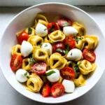 To make this fresh and zesty salad, you will need the following ingredients: - 1 package (12 oz) cheese tortellini, cooked and cooled - 1 cup cherry tomatoes, cut in half - 1 cup fresh mozzarella balls, cut in half - 1/2 cup fresh basil leaves, roughly torn - 1/4 cup extra virgin olive oil - 2 tablespoons balsamic vinegar - 1 tablespoon honey - Salt and freshly ground black pepper to taste You can easily swap some ingredients if you want a twist: - Use spinach or arugula instead of basil for a different flavor. - Swap cherry tomatoes for diced bell peppers for added crunch. - Try using ricotta or feta cheese instead of mozzarella for a new taste. - Replace honey with agave syrup for a vegan option. Fresh ingredients shine in this salad. They bring bright colors and bold flavors. - Fresh basil gives a sweet and peppery kick. - Ripe cherry tomatoes add a juicy burst with each bite. - Quality mozzarella has a creamy texture that enhances the dish. - Using good olive oil and balsamic vinegar makes the dressing rich and tasty. When you use fresh ingredients, the taste becomes vibrant and exciting. Always aim for the best quality to elevate your dishes! {{ingredient_image_2}} First, take a package of cheese tortellini. Cook it as the package says. After cooking, drain the tortellini and rinse it with cold water. This step cools it down fast. Once cooled, put the tortellini in a big mixing bowl. This is the base of your salad. Next, grab your fresh ingredients. Cut one cup of cherry tomatoes in half. Then, cut one cup of fresh mozzarella balls in half too. Tear half a cup of fresh basil leaves roughly. Add all these ingredients to the bowl with the tortellini. Gently mix everything together. This helps all the flavors blend nicely. Now, let’s make the dressing. In a small bowl, combine a quarter cup of extra virgin olive oil, two tablespoons of balsamic vinegar, and one tablespoon of honey. Add a pinch of salt and pepper for taste. Whisk these ingredients together until the dressing is smooth. Drizzle this dressing over the salad mixture. Toss everything gently again. Make sure all the salad is coated well. Taste the salad and adjust the seasoning if needed. Cover the bowl and chill it in the fridge for at least 30 minutes. This waiting time enhances the flavors. When ready to serve, give it one last gentle toss. Enjoy your fresh and zesty Tortellini Caprese Pasta Salad! To cook tortellini just right, follow these steps. Start with a large pot of salted water. Bring it to a boil before adding your tortellini. Cook according to package instructions, usually about 3 to 5 minutes. Stir gently to prevent sticking. Once they float to the top, they are done. Drain and rinse them under cold water to stop the cooking. This keeps them firm and fresh for the salad. Want to boost flavor? Here are some easy tips. Add more herbs like parsley or oregano for a fresh taste. A squeeze of lemon juice brightens the salad and adds zing. For more depth, try adding garlic or red pepper flakes. You can also mix in olives or roasted peppers for a unique twist. Each of these options adds a nice layer of flavor. To serve this salad beautifully, use a large, shallow bowl. Arrange the tortellini, tomatoes, and mozzarella in colorful layers. Top it with whole basil leaves for a pop of color. Drizzle a little extra balsamic vinegar right before serving. This adds shine and makes it even more appealing. A well-presented salad makes a great impression! Pro Tips Use Fresh Ingredients: Always opt for the freshest tomatoes and basil to enhance the flavors of your pasta salad. Chill Before Serving: Allowing the salad to chill for at least 30 minutes helps the flavors meld and intensify, making each bite more delicious. Customize the Dressing: Feel free to adjust the dressing ingredients to your taste; adding more honey for sweetness or more balsamic for tang can elevate the dish. Presentation Matters: Serve the salad in a shallow bowl and garnish it with whole basil leaves and a drizzle of balsamic vinegar for a stunning presentation. {{image_4}} You can make Tortellini Caprese Pasta Salad heartier by adding protein. Grilled chicken or shrimp works well. Simply cook the chicken or shrimp until done. Cut the chicken into bite-sized pieces. Toss them into the salad with the tortellini. This addition makes the meal more filling and adds flavor. For a vegetarian twist, replace cheese tortellini with a veggie option. Look for tortellini made with spinach or other vegetables. To make it vegan, swap the mozzarella for avocado or vegan cheese. This keeps the dish creamy and delicious without dairy. You can also add chickpeas for extra protein and fiber. You can change the salad with seasonal veggies. Roasted bell peppers, zucchini, or asparagus add great taste. Roast them in the oven until tender. Let them cool before mixing them in. This gives the dish a warm, savory touch. You can enjoy the salad all year round by using fresh, in-season produce. To store leftover tortellini caprese pasta salad, place it in an airtight container. Make sure it is sealed tightly. This will keep the salad fresh and prevent any odors from the fridge. You can also cover the bowl with plastic wrap if you do not have a container. The salad stays good for about 3 to 4 days in the fridge. Keep it cool at all times. Always check for any signs of spoilage, like odd smells or changes in color, before eating. If you notice anything strange, it's best to throw it away. I do not recommend freezing this salad. The fresh ingredients, like basil and mozzarella, do not freeze well. They may lose their texture and flavor. If you have leftovers, it's best to enjoy them fresh within a few days. Yes, you can make this salad ahead of time. I often prepare it a few hours in advance. This gives the flavors time to blend. Just chill it in the fridge until you are ready to serve. Cover it well to keep it fresh. I recommend using cheese tortellini for this salad. The cheese adds a nice richness. Fresh tortellini is great if you can find it. Dried tortellini works too; just cook it well. To boost flavor, try adding more herbs. Fresh herbs like parsley or oregano work well. You can also add garlic for a punch. If you like heat, a pinch of red pepper flakes is nice. Consider using flavored olive oil or adding more balsamic vinegar for zing. Tortellini Caprese Pasta Salad is simple and fun to make. We covered fresh ingredients, step-by-step prep, and useful tips. Remember, you can swap ingredients and add proteins for more flavor. Follow the storage tips to keep leftovers tasty. This salad is perfect for any meal. Enjoy creating your own version, and don't forget to experiment with different flavors!